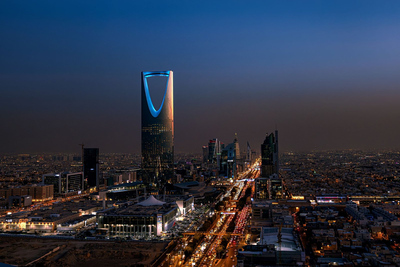 A breathtaking aerial view of Riyadh at night featuring the iconic Kingdom Centre Tower.